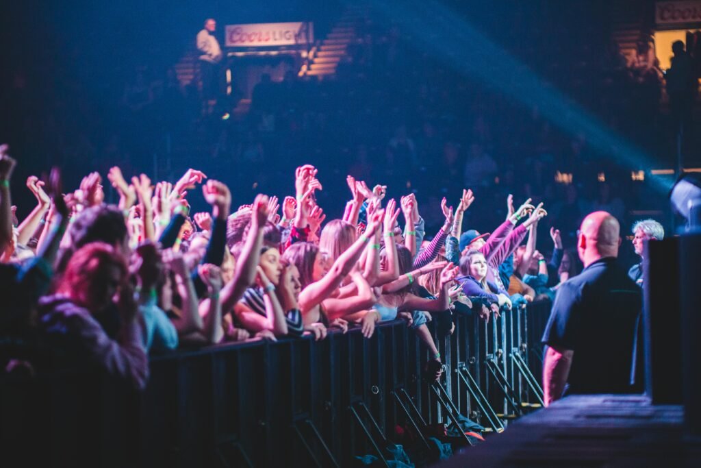 Excited crowd with hands up at a vibrant live music concert indoors.